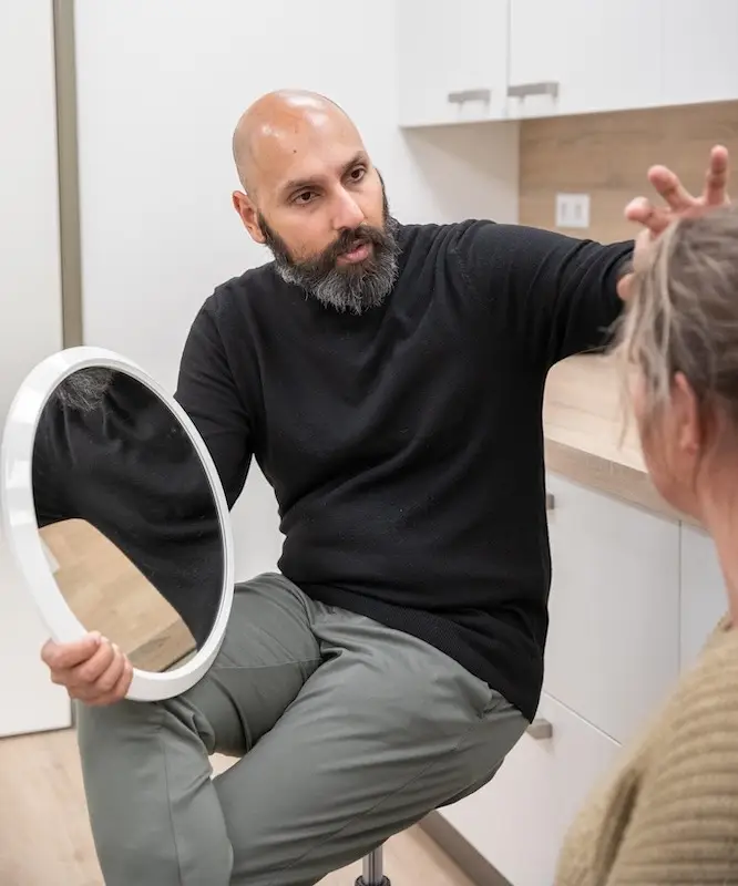 Arts bespreekt een filler behandeling met een cliënt aan de hand van een spiegel
